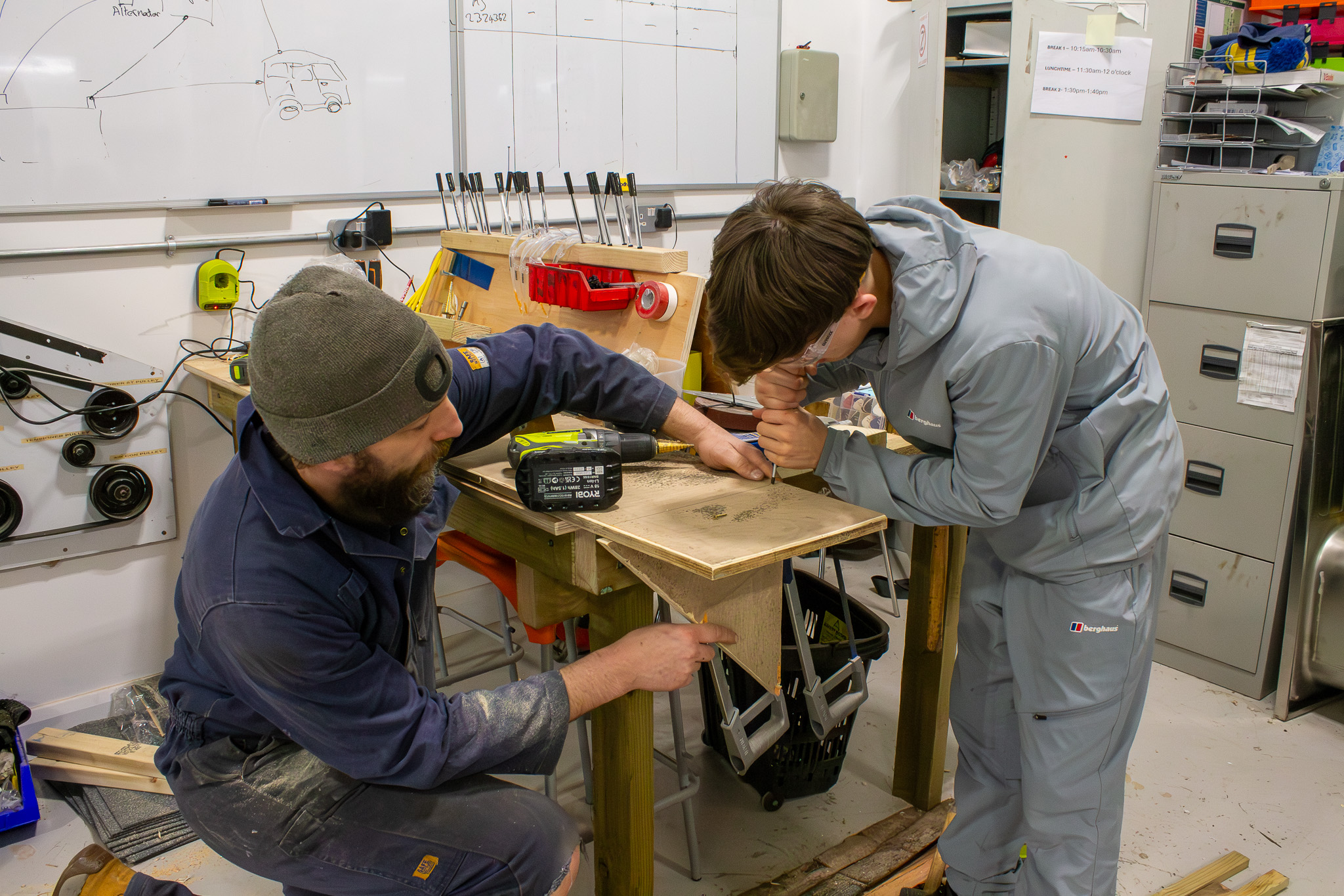 Mechanics teacher assisting student with construction workshop